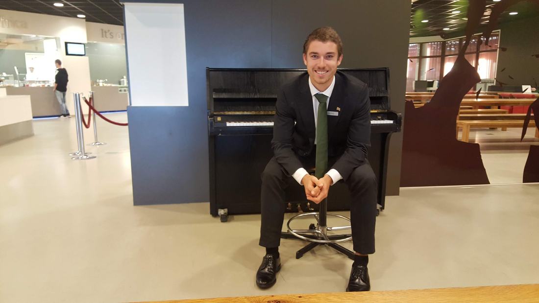 Jonas Borchert im Anzug am Klavier in der Halle der Hochschule Leeuwarden